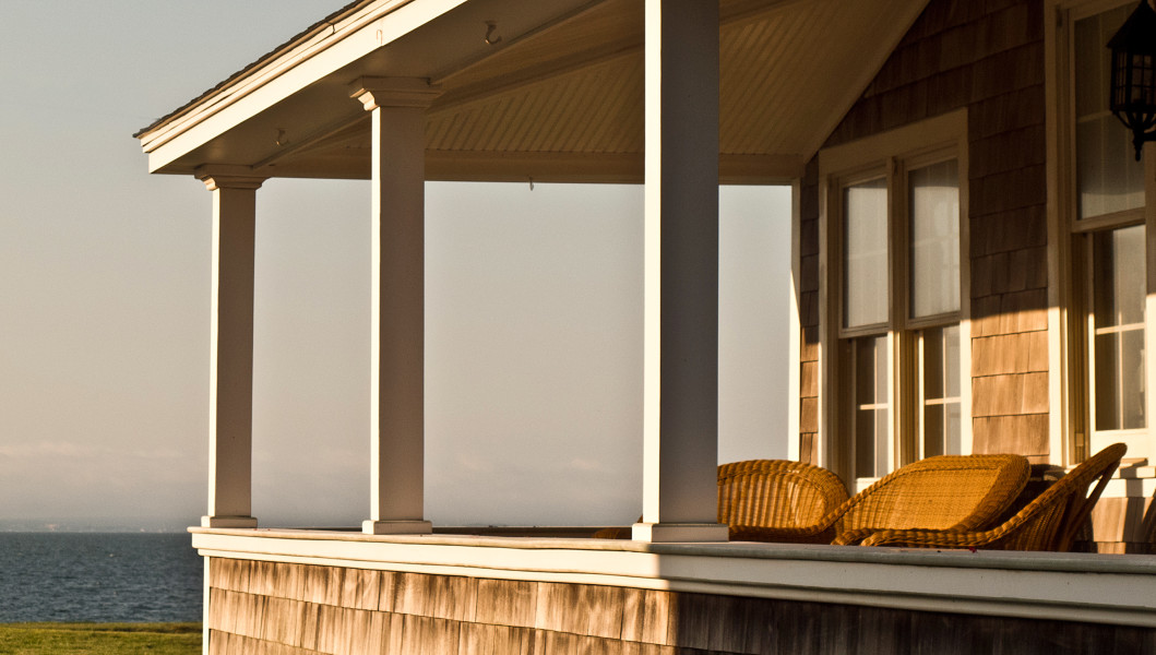 Ben Asen Personal Work Photo: Color photo of a house porch with wicker chairs at sunrise on Cape Code in Falmouth Massachusetts.