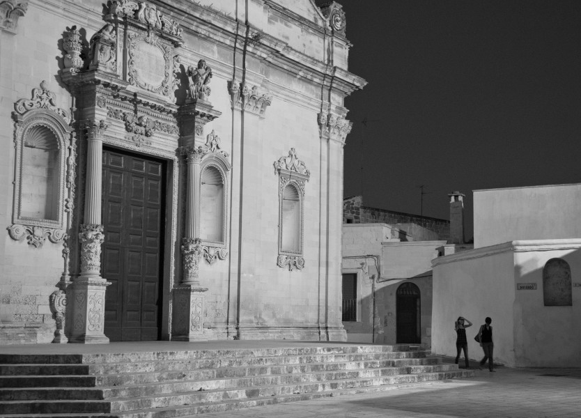 Ben Asen Personal Work Photo: Black and white photo of 2 woman walking at night past church in Muro Leccese in the Puglia region of Italy.