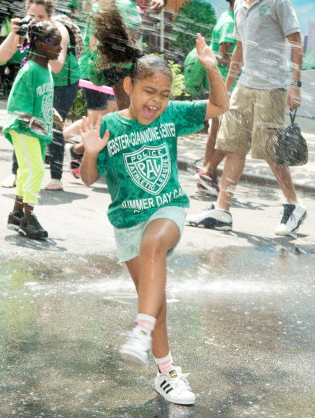 Ben Asen Editorial Photo: Police Athletic League (PAL) of NYC, young PAL girl under a fire hydrant sprinker at PAL summer event